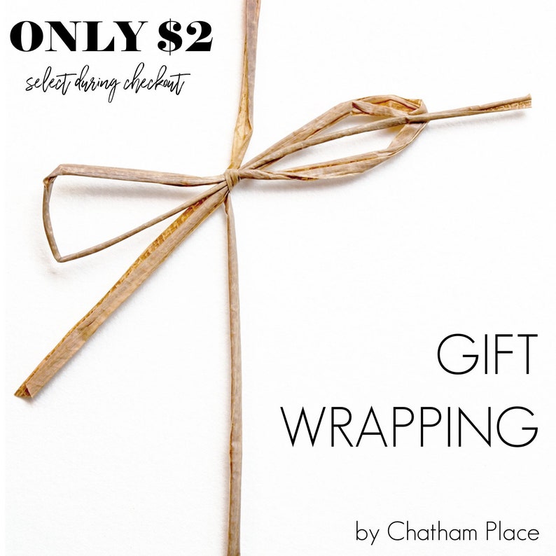 Puede incluir: Una tarjeta blanca con el texto "ONLY $2 select during checkout" y "GIFT WRAPPING by Chatham Place" en texto negro. Un lazo marr&oacute;n est&aacute; atado en la esquina superior derecha de la tarjeta.