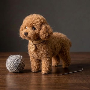 May include: A needle-felted brown poodle figurine with curly texture, wearing a tan collar with a small round tag. Beside the dog sits a ball of grey yarn and a single metal sewing needle, all rendered in a realistic, soft-sculpted style.