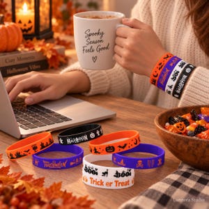 Könnte beinhalten: Eine Sammlung von Silikonarmbändern mit Halloween-Motiven wie Kürbissen, Fledermäusen, Geistern sowie den Schriftzügen "Happy Halloween" und "Trick or Treat". Die Armbänder sind in den Farben Orange, Lila, Schwarz und Weiß gehalten und werden am Handgelenk getragen.
