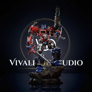 May include: A detailed Optimus Prime robot action figure standing on a rocky base. The figure is painted in red, blue, and silver, holding a long sword in its right hand and a large blaster in its left hand. The text Vivaldi Studio is visible.