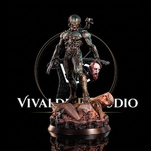 May include: A detailed figurine of a humanoid creature with a metallic, textured exoskeleton, sharp claws, and a helmet, holding a severed human head in one hand. The figure stands on a rocky, debris-filled base with the text VIVALDI STUDIO visible.