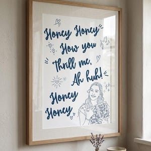 Pode incluir: Uma impressão artística emoldurada com texto em cursivo azul escuro que diz Honey Honey How you thrill me, Ah huh! Honey Honey. A impressão inclui um desenho de linha de uma pessoa segurando um livro, rodeado por corações, estrelas e notas.