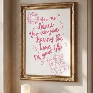 Könnte beinhalten: Ein gerahmter Kunstdruck mit rosa Strichzeichnungen einer Discokugel, Noten und drei tanzenden Figuren. Der Text lautet: You can dance, You can jive, Having the time of your life. Der Rahmen ist verziert und in Gold gehalten.