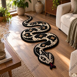 Puede incluir: Una alfombra con forma de serpiente que presenta un patrón de mechones en negro y crema con detalles de diamantes marrones. La alfombra tiene un cuerpo curvo, una cabeza detallada con ojos grandes y una lengua bífida roja sobre el suelo de madera.