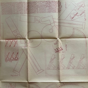 May include: A vintage paper pattern for making a toy soldier. The pattern includes instructions and diagrams for cutting and assembling the soldier. The soldier is depicted in a marching pose with a rifle and a hat.