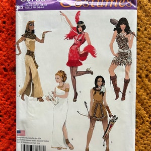 Może przedstawiać: Wzór szycia Simplicity Costumes do pięciu różnych kostiumów. Wzór zawiera sukienkę w stylu flapper, strój indiański, strój egipski, strój greckiej bogini i strój dżungli. Numer wzoru to S0793.