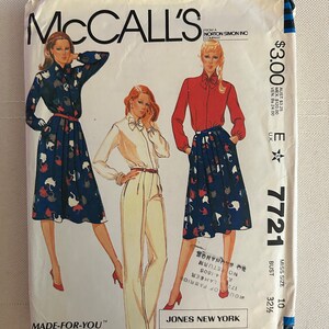 Puede incluir: Patrón de costura McCall's número 7721 para una blusa y falda de mujer. El patrón es para una talla 10, busto 83 cm. El patrón es de una empresa de Norton Simon Inc. El patrón incluye una blusa blanca con corbata de lazo, una blusa roja con corbata de lazo y una falda azul y blanca con estampado de gato. El patrón está hecho para ti y presenta pinzas de ajuste de talla de copa y líneas de corte de ajuste de hombros.