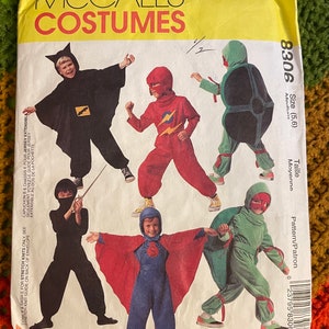 May include: A McCall's Costumes sewing pattern envelope 8306 for size medium (5,6). The front features illustrations of children wearing various superhero and character costumes, including a bat, a red lightning hero, a turtle, a ninja, and a spider hero.