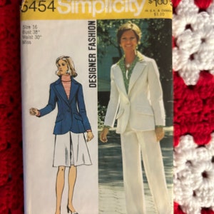 May include: A vintage Simplicity sewing pattern for a women's suit. The pattern number is 6454 and the size is 16. The pattern is for a designer fashion suit. The model is wearing a white suit with a white blouse and a white collar. The model is also wearing a white belt. The pattern is $1.00 in the USA and Canada.