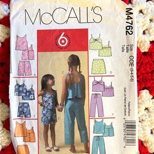 May include: A sewing pattern for a girls' sleeveless top and shorts set. The pattern includes six different styles, with options for a skirt or trousers. The pattern is for sizes 3-4-5-6. The pattern is called McCall's M4762.