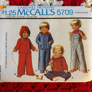 May include: A vintage sewing pattern for toddlers' unlined jacket and overalls. The pattern is from McCall's and the number is 5709. The price is $1.25. The pattern shows four different outfits for toddlers, including a red jacket and pants, a blue jacket and pants, a striped overall, and a red jacket with a blue and white patterned design.