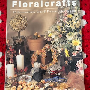 May include: The cover of a book titled "Floralcrafts" with the subtitle "50 Extraordinary Gifts & Projects, Step by Step." The image shows floral arrangements, candles, and decorative items. Authors are Gillian Souter & Catherine Lawrence.