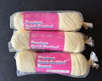 May include: Three packs of Precious Quick-Knitting Nantuk yarn in the colour Baby Yellow. Each pack contains a skein of yarn and a label with the brand name, yarn type, and colour.