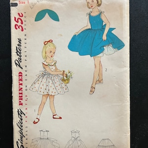 Może przedstawiać: Wzorzec szycia vintage Simplicity do sukienki dla dziewczynki. Wzorzec jest dla rozmiaru 1 i kosztuje 35 centów. Wzorzec pokazuje dziewczynkę w niebieskiej sukience i dziewczynkę w białej sukience w czerwone kropki.