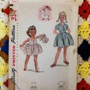 May include: Vintage Simplicity sewing pattern for a girl's dress. The pattern is for size 5 and is a 1-piece dress. The pattern includes instructions and illustrations for making the dress. The pattern is printed on paper and is in good condition.