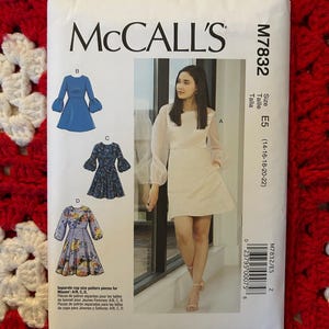 Puede incluir: Patrón de costura McCall's para un vestido, número de patrón M7832, talla E5 (14-16-18-20-22). El patrón incluye cuatro estilos de vestidos diferentes, con una modelo vistiendo uno de los estilos en la imagen.