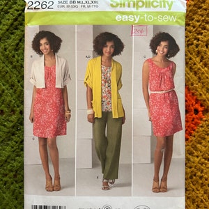 May include: Simplicity sewing pattern number 2262, easy-to-sew, size BB M, L, XL, XXL, EUR. M-XXG FR. M-TTG. The pattern shows three different styles of a dress with a floral print. The first style is a sleeveless dress with a gathered neckline. The second style is a dress with a cardigan. The third style is a dress with a bolero.