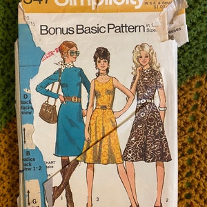 Op de afbeelding: Een vintage Simplicity naaipatroon voor damesjurken. Het patroonnummer is 547 en de prijs is $ 1,00. Het patroon bevat drie verschillende jurkstijlen: een blauwe jurk met een witte kraag, een gele bloemenjurk en een bruine bloemenjurk.