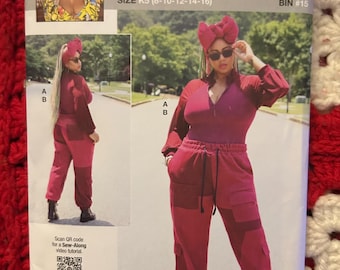 May include: Sewing pattern for a red jumpsuit with a zipper and a drawstring waist. The pattern is called "Know Me" by Mimi G and is size K5 (8-10-12-14-16). The pattern includes a QR code for a sew-along video tutorial.