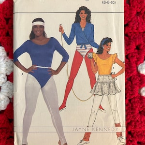 May include: A vintage sewing pattern envelope for a women's workout outfit. The pattern is by Butterick and is for sizes 6-8-10. The envelope features a photo of a model wearing a blue leotard and white tights, and another model wearing a blue and white striped leotard with a red and white striped skirt and a blue wrap top.