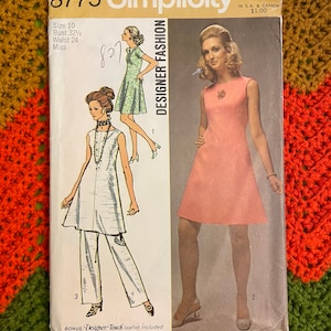 Könnte beinhalten: Vintage Simplicity Schnittmuster Nummer 8775 für ein Designer-Kleid. Das Schnittmuster ist für Größe 10, Brustumfang 82,5 cm, Taillenumfang 61 cm. Das Schnittmuster enthält Anleitungen für ein ärmelloses Kleid mit Rundhalsausschnitt und ein Kleid mit kurzen Ärmeln und Rundhalsausschnitt.
