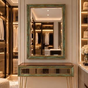 May include: A rectangular wall mirror with a distressed teal and gold frame positioned above a matching console table. The console features a glass top, a central horizontal glass-fronted drawer, and four slender gold-toned hairpin legs.