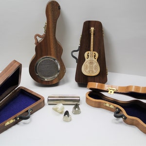 May include: Five wooden guitar cases, one with a guitar inside, and two guitar picks. The cases are all closed except for one, which is open and has a blue velvet interior.