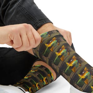 May include: A pair of crew socks featuring a repeating pattern of a yellow and green cartoon character with large ears and a long tail, set against a dark background with vertical stripes and a subtle grid texture throughout the fabric.