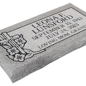 May include: A rectangular gray granite grave marker with a rough-hewn edge. The surface features an engraved cross and floral design on the left, with the text LEONA F. LUNSFORD, SEPTEMBER 15, 1943, JULY 24, 2023, and LOVING MOM, GRANDMA engraved in black.