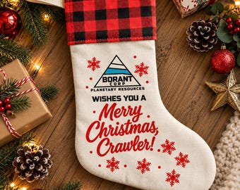 Può includere: Una calza natalizia in tessuto color crema con un risvolto a quadri rossi e neri. La calza presenta un logo stampato della Borant Corp Planetary Resources e il testo: Wishes you a Merry Christmas, Crawler! Fiocchi di neve rossi decorano la superficie.