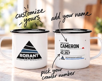 Può includere: Due tazze in smalto bianco con bordi e manici neri. La tazza a sinistra presenta un logo a triangolo nero con il testo BORANT CORP PLANETARY RESOURCES. La tazza a destra mostra CRAWLER NAME: CAMERON, CRAWLER NUMBER: 42,357 e altro testo.