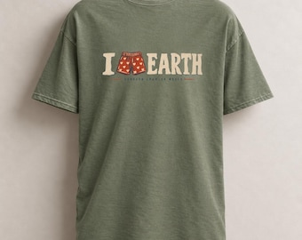 Può includere: Una t-shirt a maniche corte color verde oliva con la scritta I [icona cuore] EARTH in carattere color crema. L'icona del cuore è sostituita da un grafico di boxer rossi con un motivo a cuori bianchi. Sotto il testo appare DUNGEON CRAWLER WORLD.