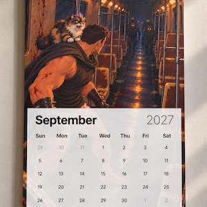 May include: A wall calendar for September 2027 featuring an illustration of a muscular figure with a cat wearing a pink crown on their shoulder, standing in a subway car facing glowing-eyed creatures. The calendar grid displays the month and year.