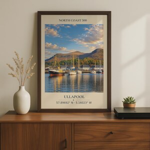 May include: A framed wall art print featuring a landscape photograph of boats docked in a harbor at Ullapool, Scotland. The text NORTH COAST 500 appears at the top, with ULLAPOOL and the coordinates 57.89692 N - 5.16023 W printed at the bottom.