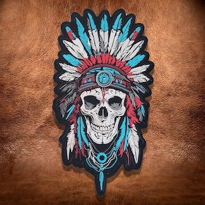 May include: An embroidered patch featuring a human skull wearing a large feathered headdress. The design uses white, turquoise, and red thread on a black background, with detailed beadwork patterns depicted around the skull's neck and forehead.