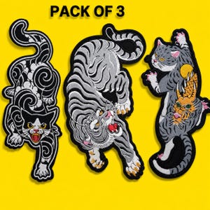 May include: A pack of 3 embroidered patches featuring stylised cat and tiger designs. The first is a black and white cat with swirling patterns, the second is a grey tiger, and the third is a grey cat interacting with a golden dragon head.