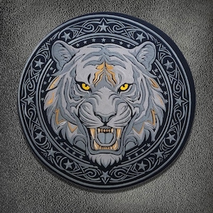 May include: A circular embroidered patch featuring a detailed tiger head with grey fur, golden accents, and piercing yellow eyes. The tiger is centred within a dark border decorated with a repeating pattern of stars and intricate knotwork designs.