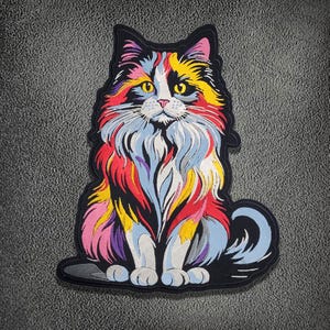 May include: An embroidered patch featuring a long-haired cat with a multi-colored coat of red, yellow, blue, and white fur. The cat is depicted in a seated position with a black border, yellow eyes, and a pink nose, showcasing detailed stitching.