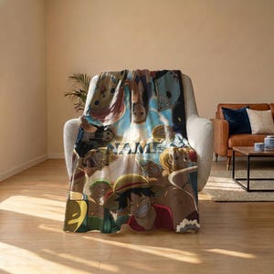 May include: A soft throw blanket featuring a vibrant, multi-coloured anime character collage from One Piece, including Luffy, Zoro, and Nami. The design incorporates the word NAME in bold, dark lettering centred among the various illustrated figures.