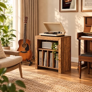 May include: A wooden record player stand with a brown wood grain finish, featuring an open top surface holding a white record player, a middle shelf with a white speaker, and a bottom section with four vertical dividers for vinyl records.