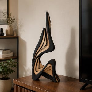 Peut inclure: Une sculpture verticale haute composée de panneaux incurvés superposés. L'objet présente des sections alternées de bois noir mat et de bois naturel clair, créant une série de formes fluides en vague qui s'élèvent vers une pointe.