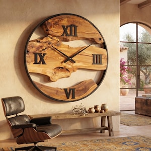 Könnte beinhalten: Eine große, runde Wanduhr mit einem Zifferblatt aus natürlichem Holz mit Baumkante, eingefasst in einen dünnen schwarzen Metallrahmen. Die Uhr zeigt schwarze römische Ziffern auf zwölf, drei, sechs und neun Uhr sowie schmale schwarze Zeiger.