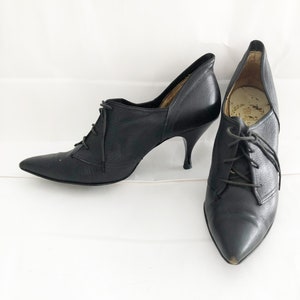 May include: A pair of black leather heeled shoes with lace-up fronts and pointed toes.