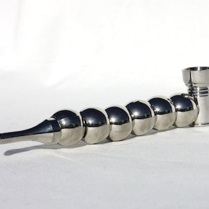 May include: A polished metal pipe with a series of spherical segments leading to a bowl and a mouthpiece. The pipe has a shiny, reflective surface, and is designed with a curved, elongated shape.