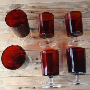 Peut inclure: Un ensemble de cinq verres à boire assortis dotés de bols cylindriques rouge foncé et de pieds en verre transparent avec des bases circulaires. Les verres sont disposés en groupe, mettant en valeur la couleur cramoisie uniforme et le design simple.