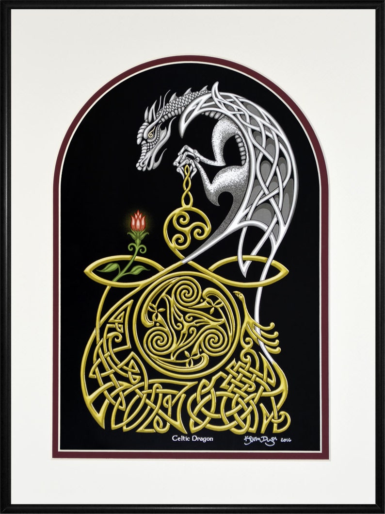 May include: A silver Celtic dragon with intricate knotwork design is holding a golden orb with a red flower below. The background is black with a maroon border.