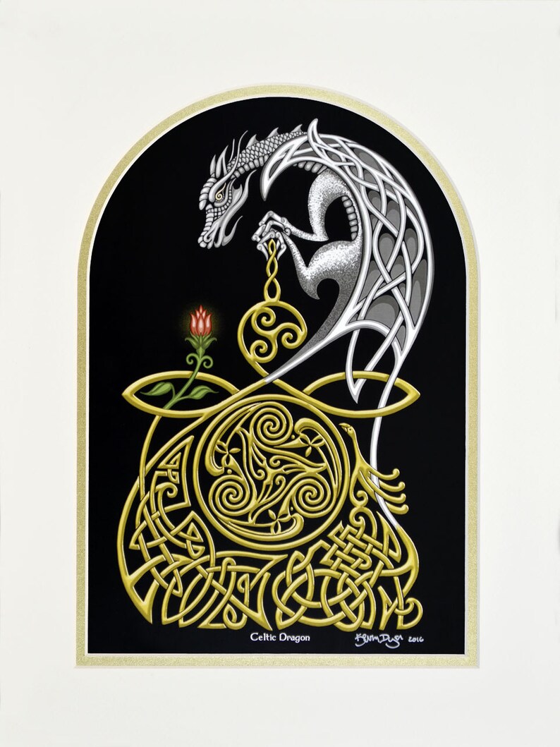 May include: A silver Celtic dragon with intricate knotwork design is depicted in a black and gold frame. The dragon is holding a golden orb with a Celtic knot design. The image is titled "Celtic Dragon" and signed by the artist.