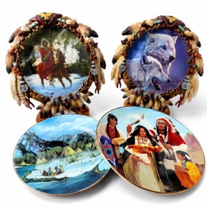 May include: Four decorative collector plates. Two plates feature ornate, feather-textured frames with turquoise accents. One depicts a rider on horseback in a snowy landscape, another shows two wolves. Two flat plates show a river scene and a group of people.