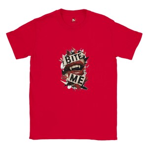 May include: A bright red short-sleeved t-shirt featuring a central graphic of red lips with sharp fangs. The design includes torn paper elements with the black text BITE ME, surrounded by dark abstract shapes and a small red kiss mark icon.