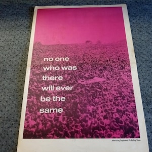 May include: A rectangular poster featuring a monochromatic magenta-toned photograph of a large crowd at an outdoor event. The white text reads: no one who was there will ever be the same. The bottom right corner includes the text: Advertising Supplement To Rolling Stone.